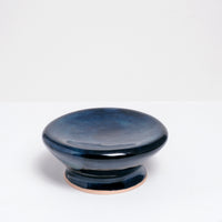 A small ceramic Maki Baxter Flat Donut Pedestal dish on show at NiMi Projects UK. The dish is glazed in deep blue, with a central dip and on a raised base. 