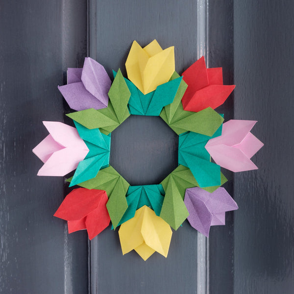 An origami wreath of geometric green leaves surrounded by purple, yellow, red and pink tulips, made for NiMi Projects origami workshops