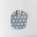 A Fuwara muslin bib made with cotton Japanese gauze in pale blue, featuring a stitched pattern of white sheep and matching striped trimming.