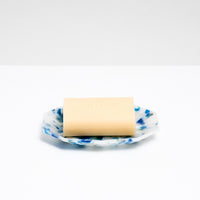 A blue and white recycle plastic polygon-shaped soap dish in white and blue, with a bar of off-white soap on it. Made by Buoy in Japan and available at NiMi Projects UK.