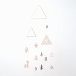 Forest mobile, designed by Sukima and made in Japan, featuring two brass wire triangles, one wood triangle and wooden cutouts of a bird, deer, snowman, stocking and trees. Available at NiMi Projects UK