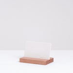 A white minimalist Ceramic Japan credit card shaped stone aroma diffuser, held upright in a natural wooden stand, made in Japan and sold at NiMi Projects UK.