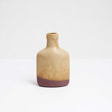 A  slim, flat bottle-shaped mini vase with a yellow, satin dip glaze and an exposed natural clay. Made by Angle and on show at NiMi Projects UK.