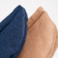 Detail image of the top of two pot holder oven mitts, made in Japan by Ban Inoue. The pot holders are semi-circle, padded and made with a muslin fabric. Colours from left to right: navy blue, brown. Available at NiMi Projects UK.