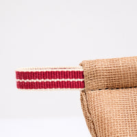 A detail image of the corner of a brown pot holder oven mitt. The mitt is padded and made with muslin and features a braided hanging cord in red and white. Made in Japan and available at NiMi Projects UK.