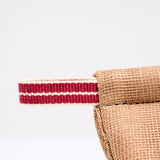 A detail image of the corner of a brown pot holder oven mitt. The mitt is padded and made with muslin and features a braided hanging cord in red and white. Made in Japan and available at NiMi Projects UK.