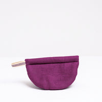 A burgundy Ban Inoue pot holder oven mitt. The mitt is lightly padded muslin, oval and folded at the centre to appear semicircle and features a braided hanging cord on the left corner. Made in Japan and on show at NiMi Projects UK.