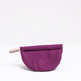 A burgundy Ban Inoue pot holder oven mitt. The mitt is lightly padded muslin, oval and folded at the centre to appear semicircle and features a braided hanging cord on the left corner. Made in Japan and on show at NiMi Projects UK.