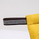 A detail image of the corner of a yellow pot holder oven mitt. The mitt is padded and made with muslin and features a braided hanging cord in red and white. Made in Japan and available at NiMi Projects UK.