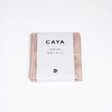 A folded beige Caya muslin dish cloth or kitchen cloth, made using Japanese cotton mosquito net weaving techniques by Ban Inoue. The cloth is wrapped in a white, paper label featuring the Caya brand name and it’s available at NiMi Projects UK.