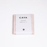 A folded pink Caya muslin dish cloth or kitchen cloth, made using Japanese cotton mosquito net weaving techniques by Ban Inoue. The cloth is wrapped in a white, paper label featuring the Caya brand name and it’s available at NiMi Projects UK.