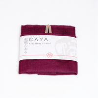 A folded grape burgunday Caya kitchen towel, made from Japanese muslin woven using traditional mosquito net weaving techniques. The tea towel is made in Japan by Ban Inoue and wrapped in a white paper label with the Caya logo. Available at NiMi Projects UK.