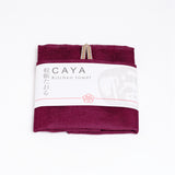 A folded grape burgunday Caya kitchen towel, made from Japanese muslin woven using traditional mosquito net weaving techniques. The tea towel is made in Japan by Ban Inoue and wrapped in a white paper label with the Caya logo. Available at NiMi Projects UK.