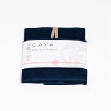 A folded navy blue Caya kitchen towel, made from Japanese muslin woven using traditional mosquito net weaving techniques. The tea towel is made in Japan by Ban Inoue and wrapped in a white paper label with the Caya logo. Available at NiMi Projects UK.