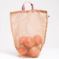 A medium, transparent brown muslin Vegetable tote bag, made in Japan by Ban Inoue using traditional mosquito net weaving techniques. The bag has  several onions inside and has a folded and stitched base for support and short top handles. On show at NiMi Projects UK.