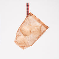 A small, transparent brown vegetable bag, made by Ban Inoue using traditional mosquito net weaving techniques. Made in Japan, it’s a simple rectangle shape with stitched corners at the bottom for structure. One corner features a braided cord to hang it with. Available at NiMi Projects UK.