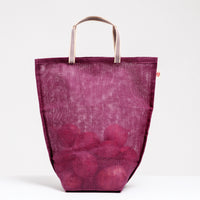 A large burgundy Vegetable tote bag filled with onions, made by Ban Inoue in Japan with muslin woven using traditional mosquito net techniques. The bag is slightly transparent has a folded and stitched base for support and short top handles. Available at NiMi Projects UK.