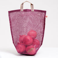A medium burgundy Ban Inoue Vegetable, transparent tote bag, filled with several onions and made in Japan with muslin woven using traditional mosquito net techniques. The bag has a folded and stitched base for support and short top handles. Available at NiMi Projects UK.