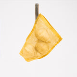 A yellow, small transparent vegetable bag, made by Ban Inoue using traditional mosquito net weaving techniques. Made in Japan, it’s a simple rectangle shape with stitched corners at the bottom for structure. One corner features a braided cord to hang it with. Available at NiMi Projects UK.