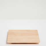 A large square Legnatec hinoki (Japanese cypress) wood coaster at 12cm x 12cm, with a tapered base. Available at NiMi Projects UK.