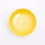 A top view of a Mino-yaki Japanese porcelain plate with fluted edge in bright yellow. On show at NiMi Projects UK.