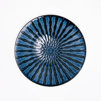 A top view of a Mino-Yaki Tokusa Blue Platter, with an indigo blue overglaze and a radial striped pattern of black underglaze, exposed by indents in the porcelain.  Available at NiMi Projects UK.