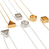Six Shape in Shape necklaces made by Kei Tominaga, each two layers of hollow shapes threaded onto a delicate thin chain. From left to right: silver triangles, gold triangles, silver squares, silver circles, gold circls and gold squares.