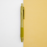 An olive green Uniball jetstream retractable pen laid out on a bicolour (white/yellow) background, available at NiMi Projects UK.