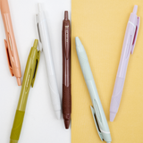 Set of a coral pink, sage green, white, brown, mint green and lilac Uni-ball jetstream gel-ink retractable pens on a bicolour white/yellow background, on show at NiMi Projects UK.