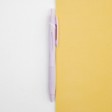 A lilac Uniball jetstream retractable pen laid out on a bicolour (white/yellow) background, available at NiMi Projects UK.