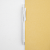 A white Uniball jetstream retractable pen laid out on a bicolour (white/yellow) background, on show at NiMi Projects UK.