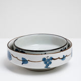 Two Japanese vintage porcelain bowls, one large and one medium sized, featuring a border design of blue underglaze bunches of grapes and vine leaves and a crackle glaze.