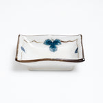 Close up of small Japanese vintage porcelain dish featuring a border design of blue underglaze bunches of grapes and vine leaves and a crackle glaze.