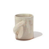 A large white, lightly speckled, glazed ceramic mug designed with its handle on a slant to make it easier to hold and tilt. Hand made by Angle in Japan and available at NiMi Projects UK.