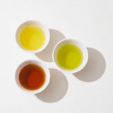 Ariel view of three white cups of Awaido Japanese tea. Clockwise from top: a yellow coloured tea, a green tea and a brown tea. Image ©AWAIDO