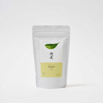 A white pouch of Awaido Japanese green tea leaves. The pouch has a rectangle label with a green illustration of a tea leaf and the name of the tea in Japanese kanji. Below the kanji is a light green section of the label with the name in English: Sumi. Image ©AWAIDO