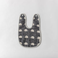 A Fuwara muslin bib made with cotton Japanese gauze in navy blue, featuring a stitched pattern of white hedgehogs and grey striped trimming.