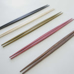 Five pairs of Style of Japan's Hashi double-end tapered wooden Ryokuchi chopsticks, lined up at an angle. Each pair is a different colour from top to bottom: black, natural, green, red and brown. Made in Japan and available at NiMi Projects UK.