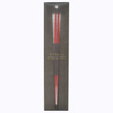 A pair of Style of Japan  red, Hashi wooden chopsticks in black paper packaging.