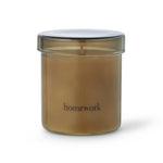 A candle encased in an amber glass jar and labeled "homework"