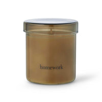 A candle encased in an amber glass jar and labeled "homework"