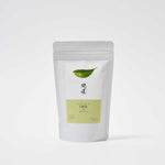 A white pouch of Awaido Japanese green tea leaves. The pouch has a rectangle label with a green illustration of a tea leaf and the name of the tea in Japanese kanji. Below the kanji is a green section of the label with the name in English: Iro. Image ©AWAIDO