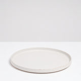 A side view of a large, round Kihon no Utsuwa white, Japanese dinner porcelain plate. Made in Japan from recycled ceramics and local clays and available at NiMi Projects UK.