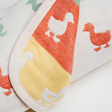 Closeup view of a reversible Japanese cotton muslin blanket with a pattern of rows of multicolour duck motifs. Made in Japan by Fuwara and available at NiMi Projects UK.