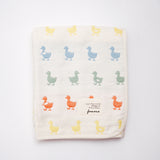 A folded off-white Japanese cotton muslin blanket with a pattern of rows of multicolour duck motifs. Made in Japan by Fuwara and available at NiMi Projects UK.