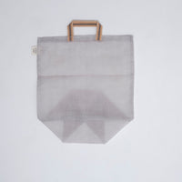A medium, transparent silvery grey muslin Vegetable tote bag, made in Japan by Ban Inoue using traditional mosquito net weaving techniques. The bag has a folded and stitched base for support and short top handles. On show at NiMi Projects UK.