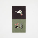 A square Japanese Motif Mini Card, featuring an illustration of Japanese partridge on a black backround and a shochikubai motif (plum blossom, bamboo and pine on a green background. Printed in Japan and available at NiMi Projects UK.