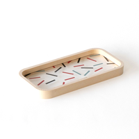 A rectangular Moheim Bou Pen Tray, with wood sides that curve at the corners and a transparent base featuring a pattern of black, red and pale blue lines.