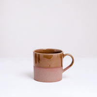 An earthenware mug half-dipped from the top in a glossy taupe glaze. Made in Japan by Angle ceramics and pictured at NiMi Projects UK.