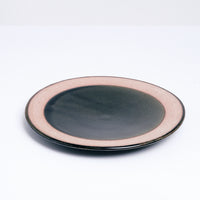 A mino-yaki earthenware small plate, designed by Angle and made in Japan, featuring a central circle of glossy deep-green glaze and a matching line of green on its outer rim. An exposed, unglazed clay border of the plate showcases the speckled texture of the raw orange clay. Available at NiMi Projects UK.